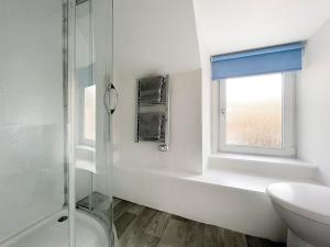 a bathroom with a shower and a sink and a window at Academy Street Cottage in Tain