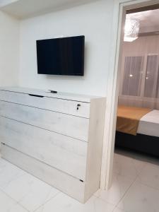 a bedroom with a dresser with a tv on a wall at D&B Apartment 3 in Paralia Katerinis