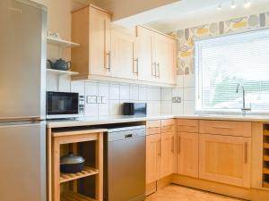 a kitchen with wooden cabinets and a stainless steel dishwasher at Torvean in Wareham