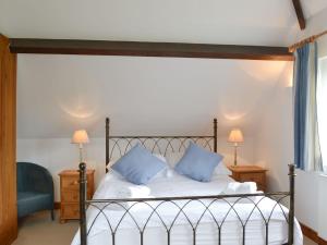 um quarto com uma cama com duas almofadas azuis em The Stables em Eardisland