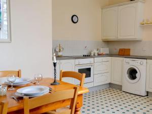 uma cozinha com uma mesa de madeira e uma cozinha com uma máquina de lavar roupa em Cloud Howe em Arbuthnott