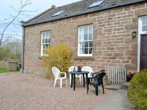 uma mesa e cadeiras em frente a uma casa de tijolos em Cloud Howe em Arbuthnott