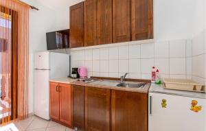 kuchnia z drewnianymi szafkami, zlewem i lodówką w obiekcie Cozy Apartment In Jurandvor w mieście Jurandvor