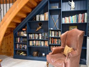 una biblioteca con paredes azules y una silla marrón en Hadrians Garden Cottage - Uk3323, en Bardon Mill