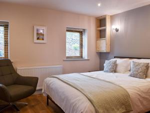 a bedroom with a bed and a chair and two windows at Hen House - Uk31827 in Rimington