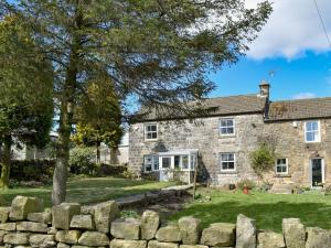 a stone house with a stone wall in front of it at Span Carr Cottage in Ashover