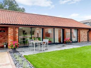 an extension to a house with a patio and grass at The Dairy in Elsham