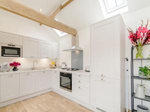 a white kitchen with white cabinets and a skylight at The Dairy in Elsham