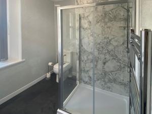 Brigham的住宿－The Oak Apartment，一间带卫生间的浴室内的玻璃淋浴间