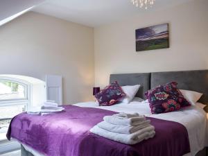 a bedroom with a purple bed with towels on it at Chapel House in Bardon Mill