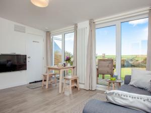 a living room with a couch and a table and some windows at Meadows Edge - Uk30951 in Perranzabuloe