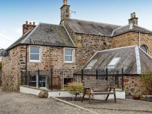 a brick house with a bench in front of it at Carse View Cottage in Abernethy