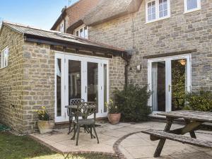 a patio with a picnic table and a building at Myrtle Cottage in Puncknowle