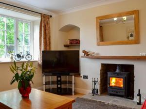 sala de estar con TV y chimenea en Keldholme Cottages 2 - Uk11488 en Kirkbymoorside