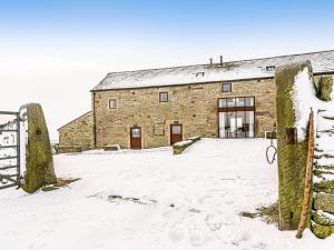 un grand bâtiment en briques dans la neige dans l'établissement Waters Edge - Uk32390, à Dunford Bridge