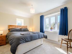 a bedroom with a bed with blue curtains and a window at Rathlin Cottage in Cambridge