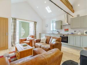 a living room with leather furniture and a kitchen at Abigails Cottage in Trimdon Grange