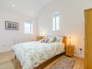 um quarto com uma cama, uma mesa de cabeceira e 2 janelas em Abigails Cottage em Trimdon Grange