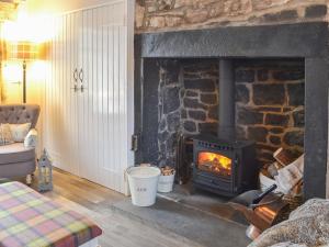 a stone fireplace in a living room with a stove at Lake View Cottage in Falstone