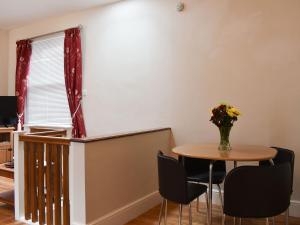 a dining room with a table and chairs and a vase of flowers at Haven Hideaway in Harwich