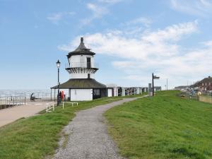 a lighthouse on a grassy hill next to the ocean at Haven Hideaway in Harwich