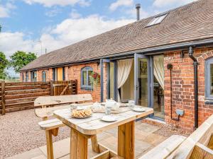 una mesa de madera frente a una casa de ladrillo en The Coach House - Uk32461 en Burlton