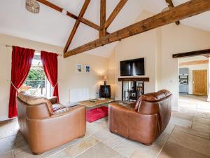 een woonkamer met 2 leren stoelen en een televisie bij The Coach House - Uk32461 in Burlton