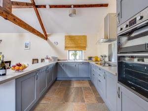 a large kitchen with blue cabinets and wooden beams at The Coach House - Uk32461 in Burlton