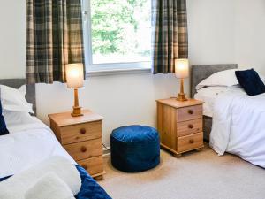 a bedroom with two beds and two lamps and a window at Woodend Farmhouse Halmyre in Haugh of Urr