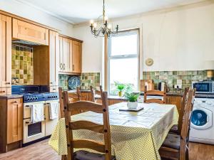 a kitchen with a table with chairs and a dining room at Maisie Cottage in Saint Monance