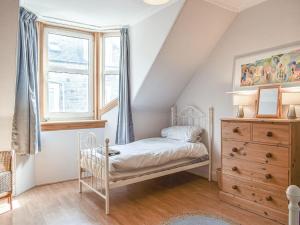 a bedroom with a white bed and a window at Maisie Cottage in Saint Monance