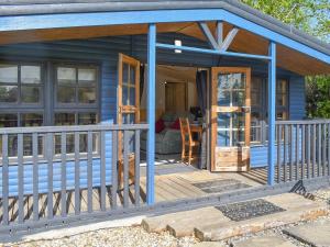 a blue tiny house with a porch and a deck at The Cabin in Elmstone