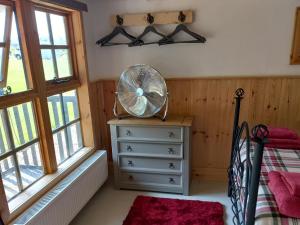 a bedroom with a fan on a dresser and windows at The Cabin in Elmstone
