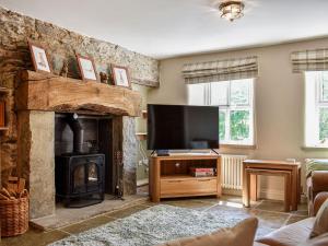 sala de estar con chimenea y TV de pantalla plana en Conn Cottage, en Bampton