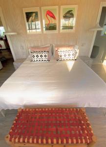 a large white bed with a red rug on it at Rooster Beach - Hope Town, Elbow Cay in Lubbers Quarters Cay