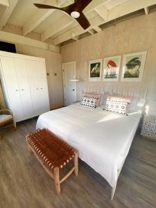- une chambre avec un grand lit blanc et un banc dans l'établissement Rooster Beach - Hope Town, Elbow Cay, à Lubbers Quarters Cay