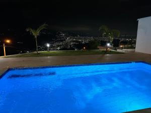 a blue swimming pool at night with a city at Se Alquila Hermosa Cabaña Turquesa in Lebrija