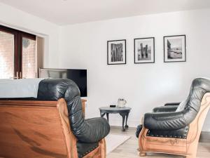 a bedroom with a bed and two leather chairs at The Cinder Warren in Whitby