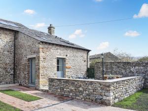 a stone cottage with a stone retaining wall and a patio at Ower Yonder in Ingleton