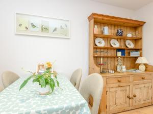 a dining room with a table and a wooden cabinet at River Test View in Chilbolton