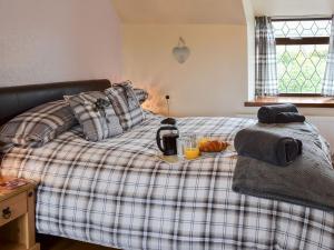 a bed with a plaid blanket with a tray of food on it at Puffin Cottage in Bempton