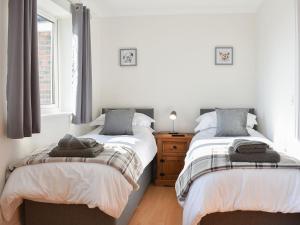 a bedroom with two beds and a dresser and window at Chapel House in Dearham