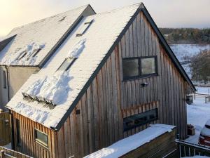 a wooden building with snow on the roof at Drovers Apartment in Tomatin
