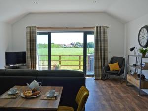 ein Wohnzimmer mit einem Sofa und einem Tisch in der Unterkunft Harrys Den in Chapel Saint Leonards