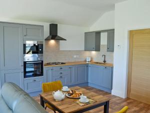 uma cozinha com armários azuis e uma mesa de madeira em Harrys Den em Chapel Saint Leonards