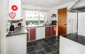 uma cozinha com armários brancos e pisos em azulejo preto em Amazing Home In Sams With Kitchen em Nordby