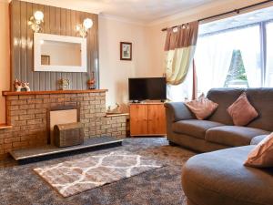 a living room with a couch and a fireplace at Kimberley Bungalow in Alness