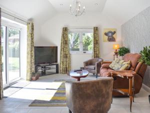 uma sala de estar com um sofá e uma televisão em Trees Annexe em Gurnard