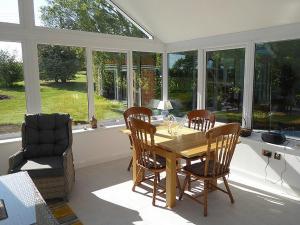 uma sala de jantar com mesa, cadeiras e janelas em Trees Annexe em Gurnard