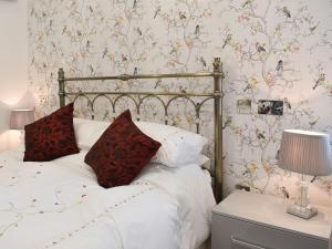 um quarto com uma cama com lençóis brancos e almofadas vermelhas em Trees Annexe em Gurnard